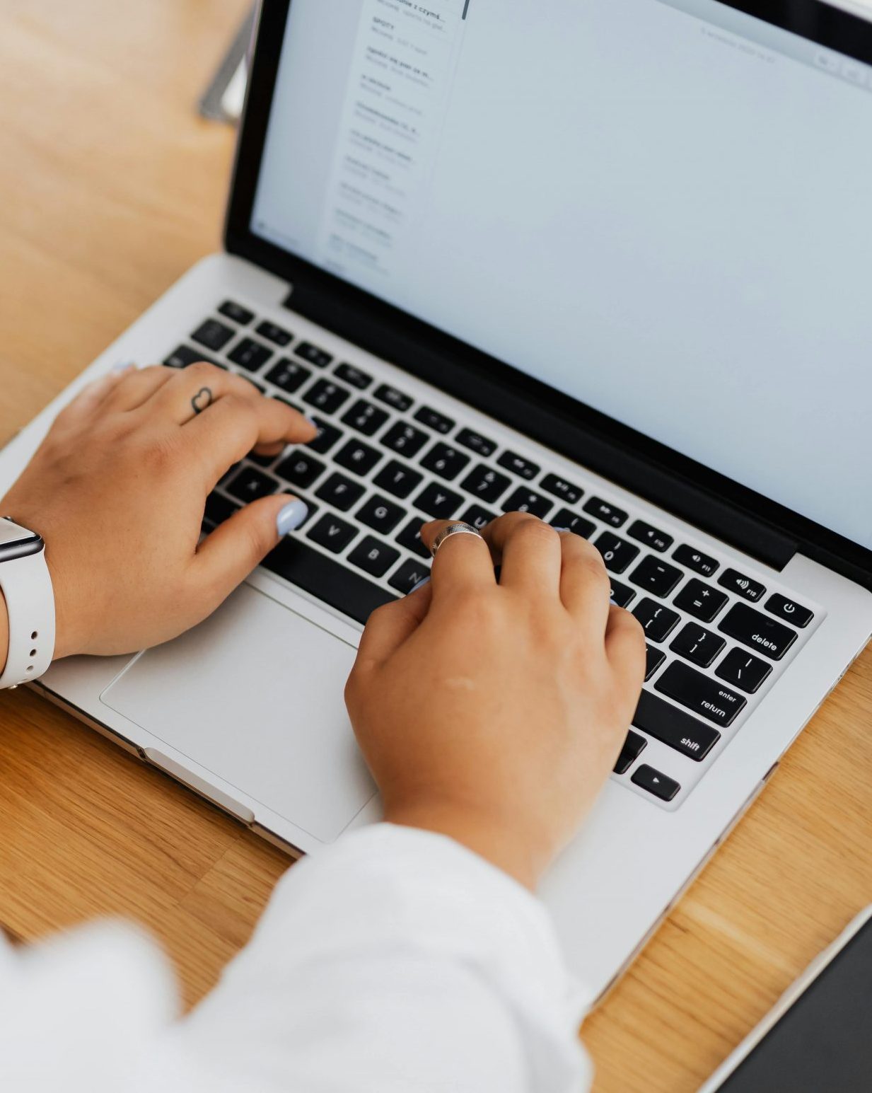 High angle shot of a person typing on a laptop, focused on hands and keyboard.